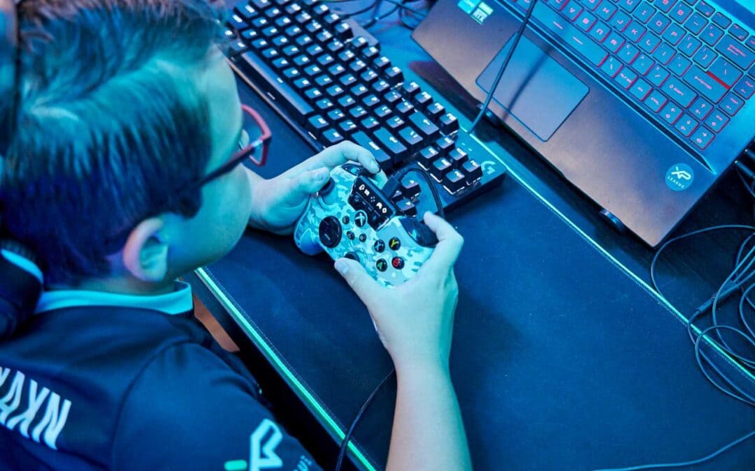 boy holding a game controller in front of a laptop
