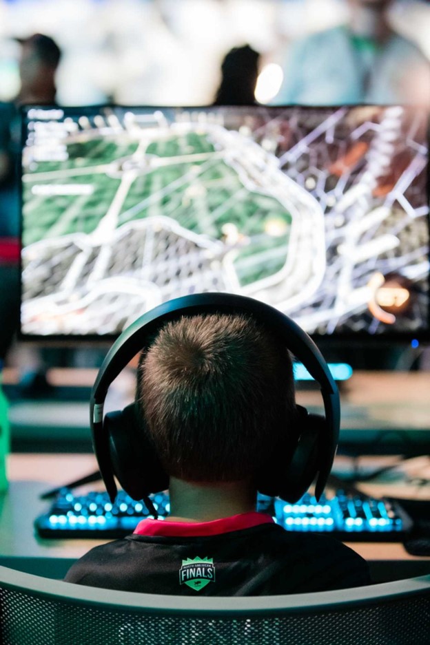 young gamer with large headset focuses on a game on screen