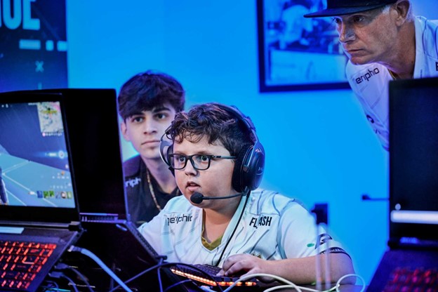 Boy playing video game with mentor behind him